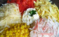 Салат с крабовыми палочками, кукурузой, яйцом, сыром и помидорами